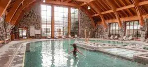 Mujer en la piscina termal techada del Hotel Termas de Puyehue, rodeada de arquitectura de madera y vegetación